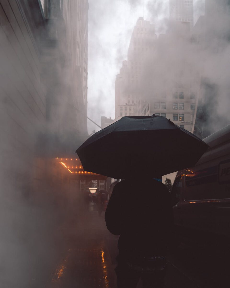 person wearing black jacket using black umbrella